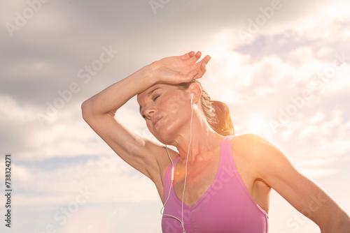 sporty woman hot after exercise in the sun, hand to head