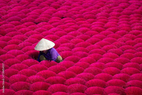 Woman surrounded by colourful bundles of incense at an incense factory in Hanoi, Vietnam