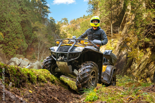 Man on quad bike. Racer rides off-road. Quad bike for racing in mountainous areas. ATV driver looks around. Man takes part in ATV racing. Guy with quad bike in picturesque nature. Extreme trip