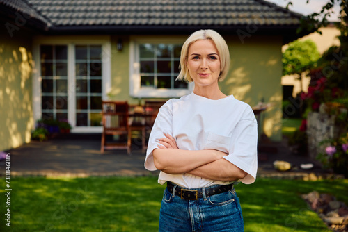 Portrait of happy mature woman standing outside her house.