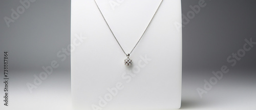 A sleek pendant necklace with a minimalist design, displayed on a soft gray background.