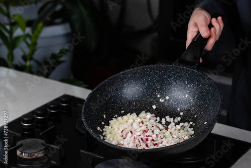 Close up of Chef cook hands cooking roasted onion and garlic in frying wok pan on gas stove.