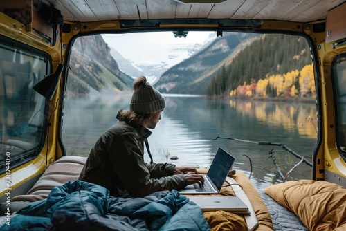 A person finds a tranquil remote working spot inside a van, with a captivating view of a serene mountain lake and autumnal forest, reflecting the ideal work-life balance