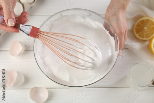 Woman making whipped cream with whisk at white wooden table, above view