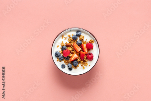 Healthy breakfast bowl with ingredients granola fruits Greek yogurt and berries on a pink background top view. Weight loss, healthy lifestyle and eating concept