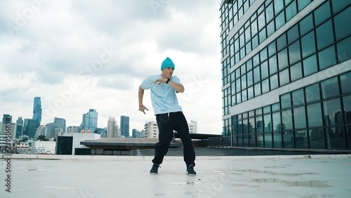 Stylish caucasian dancing man performing break dance at skyscraper. Portrait image of young happy man practicing street dance performance choreographer in modern urban city. Paris style. Endeavor.