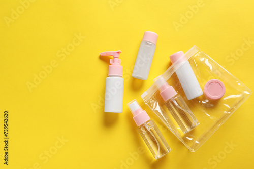 Plastic bag with cosmetic travel kit on yellow background, flat lay. Space for text