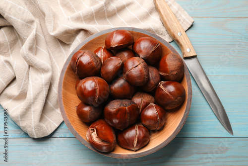 Fresh edible sweet chestnuts and knife on light blue wooden table, flat lay