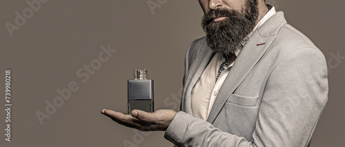 Man is holding perfume. Man holding a perfume bottle and spraying fragrance on hand. Man perfume, fragrance. Masculine perfume. Perfume or cologne bottle
