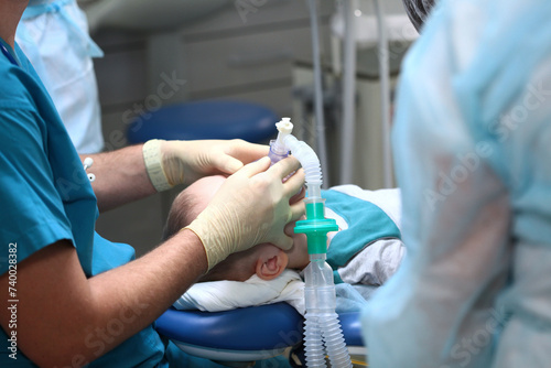 Oxygen mask on the child's face during surgery. Pre-oxygenation for general anesthesia. Dental treatment for a child. Surgical equipment.