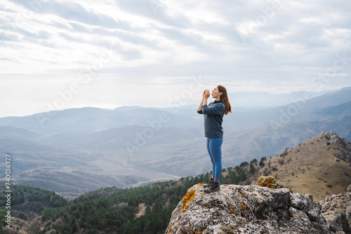 woman screaming celebrating vacation at sunset in the mountain successful woman hiker shouting hiking on mountain peak rock edge traveler screams against the backdrop of the mountain peak