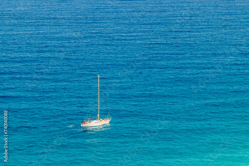 Velero navegando por aguas turquesas. Vista cenital de un velero navegando por el mar Mediterráneo. Playa de Los Muertos, Almería, España.