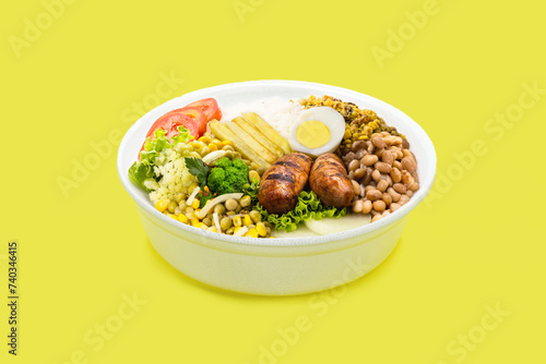 marmita or marmitex, Brazilian home-delivered lunch meal, with rice, sausage, farofa and salad, beans, copy space, yellow background