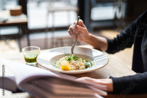 Mid-Section Of Woman Eating Rice And Reading A Book