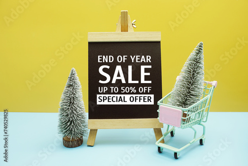 End of year sale text message on chalkboard easel stand with Christmas tree decoration