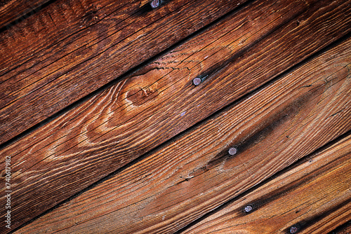 Brązowe chropowate drewniane deski przybite gwoździami z widocznymi słojami i sękami ułożone ukośnie – tło, tekstura