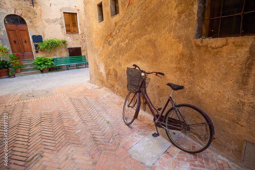 Serene corner of Pienza: vintage bike, old house, and tranquil atmosphere.