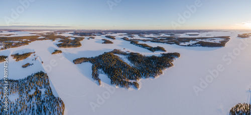 Aerial view over snow covered taiga landscape with boreal forest and frozen lakes in south Lapland, Finland at sunset 