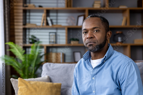 Thoughtful african american man sitting in a living room with a contemplative expression