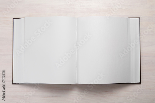 One open photo album on wooden table, top view