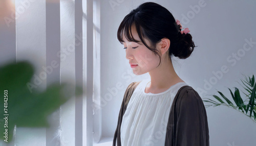 明るくシンプルな部屋で、ひとり静かに物思いにふける、若いアジア人の女性の横顔