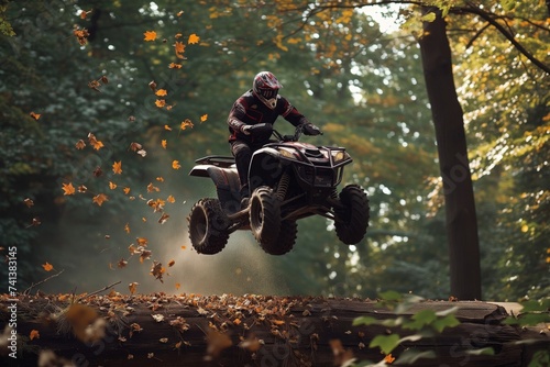 rider jumping atv over a forest log, leaves fluttering down