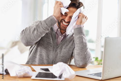 Man, laptop and frustrated at work with paper on desk, overtime and stress to meet deadline. Startup, office and documents for research on information for business growth with notes and upset