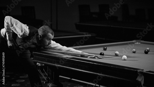 Stylishly dressed guy confidently playing in snooker game. Advertisement image of trendy billiards lounge or bar. Black and white. Concept of billiards sport, gambling, hobby, leisure, game
