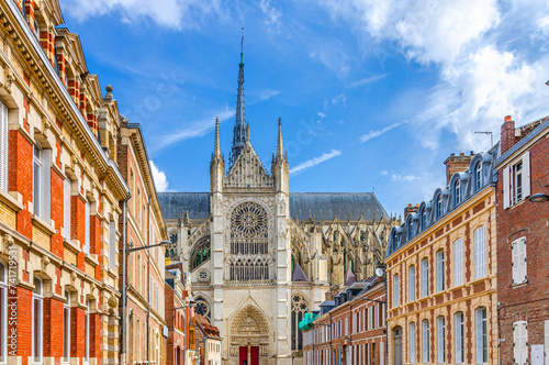 Amiens cityscape of old historical city centre with narrow pedestrian street, typical buildings and Amiens Cathedral Basilica of Our Lady Notre-Dame, blue sky, Hauts-de-France Region, Northern France