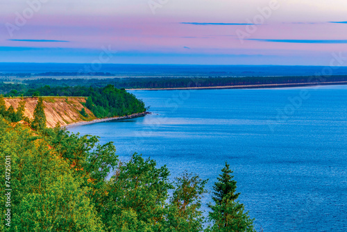 Seascape - the shore of Lake Onega in selective focus against the background of clouds at sunset.Karelian landscape.Nature, ecology, ecotourism.Forest lake.