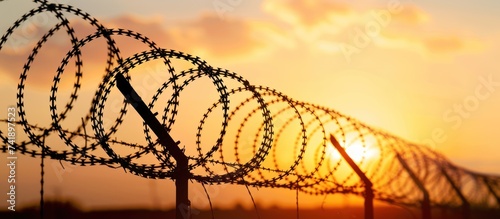 Silhouette of barbed wire against a warm sunset