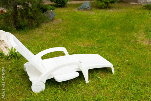 White plastic sun lounger on a green lawn
