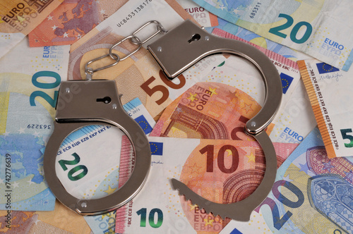 Concept de délit financier avec des menottes sur un fond en billets de banque en euro