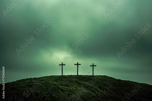 three crosses on top of hill stand against a darkening sky.