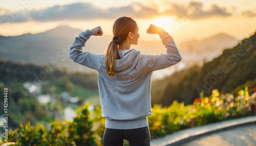 woman flexing biceps, gazing at sunrise, symbolizing motivation and empowerment