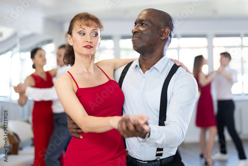 Couple of adult man and adult woman dancing waltz in studio