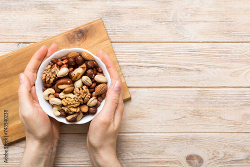 Woman hands holding a wooden bowl with mixed nuts Walnut, pistachios, almonds, hazelnuts and cashews. Healthy food and snack. Vegetarian snacks of different nuts