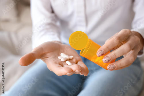 Mature woman taking pills in living room, closeup