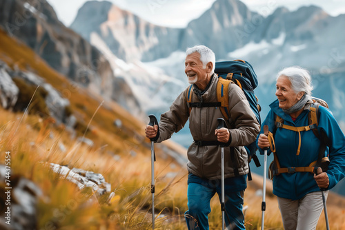 Senior pensioner couple with nordic walking poles hiking in the mountains