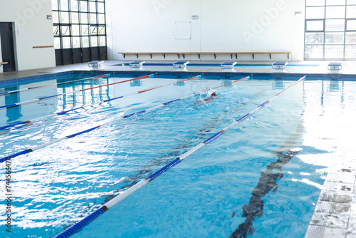 A lone swimmer practices in an indoor pool, with copy space