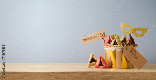 Jewish holiday Purim concept with colorful hamantaschen cookies and carnival mask on wooden table over gray background