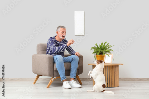 Mature man with cute Jack Russell terrier sitting in armchair at home
