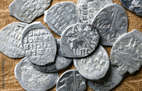 Ancient Russian coins 16th century close-up, pile of silver money of Tsar Ivan IV the Terrible. Top view of metal flakes on vintage background. Concept of old Russia, antique, collection