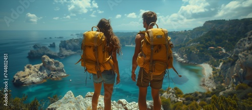 a man and a woman with backpacks are standing on top of a mountain overlooking the ocean