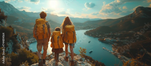 a family with backpacks standing on top of a mountain overlooking a lake