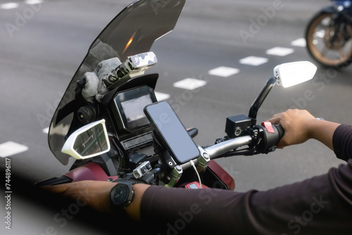 Close up photo of motorcycle or maxi scooter driver in helmet use smartphone application to find geo location. Uses phone mobile technology in every day life. big city traffic jam and future app