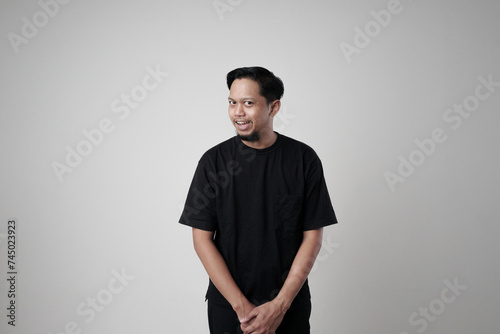 Portrait of a man making a silly funny face, showing a funny brainless silly facial expression posing with a stupid smile, playing around. An isolated indoor studio shot on a gray background