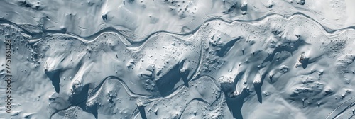 Abstract aerial view of a glacier with deep blue crevasses and textured ice patterns.