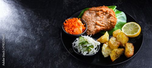 Pork cutlet coated with breadcrumbs with potatoes and salads