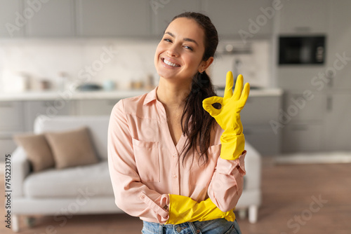 Smiling woman with yellow gloves giving okay sign